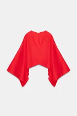 Kimono o capa asimétrica de color rojo vibrante, con escote en V pronunciado y mangas amplias tipo murciélago. La tela parece tener textura de lino.