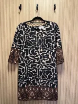 Vestido corto con estampado abstracto en negro y beige, con mangas 3/4 y detalles de estampado geométrico en puños y ruedo.