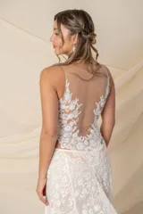 Vestido de novia largo de encaje color marfil con fondo de tul color nude, escote en V y cola de encaje con terminación de blonda.