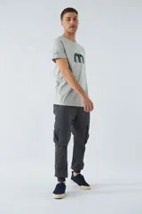 Pantalón cargo gris oscuro, corte slim, con cierre de botón y cremallera, trabillas para cinturón, bolsillos cargo con botón y puños ajustados.