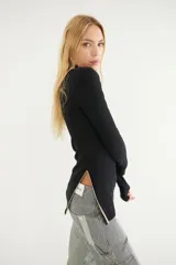 Blusa negra de tejido de punto con cuello alto y abertura en el pecho con cierre.