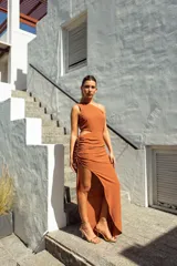 Vestido largo color ladrillo, de un solo hombro, con abertura cut-out en la cintura y falda irregular con frunces.