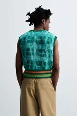 Chaleco cropped de punto con cuello en V, estampado a cuadros en tonos verde y celeste, y ribete inferior a rayas horizontales en verde y naranja.
