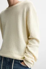 Jersey de hombre color lila, tejido en hilatura de algodón con textura. Tiene cuello redondo, manga larga y acabados en rib con detalle de vuelta.