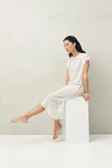 Top largo color blanco, confeccionado en tejido liviano con transparencia y caída fluida.