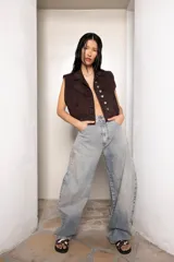 Chaleco vintage de jean color marrón oscuro, con cuello solapa, cierre frontal con botones metálicos, bolsillos delanteros con solapa y corte oversize.