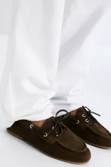 Zapato náutico color marrón de serraje con detalle de pespuntes en el cuerpo y pasados en los laterales. Cierre mediante cordones y suela efecto engomado.