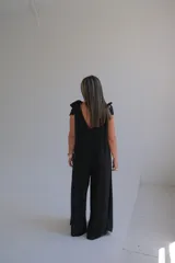 Mono largo negro con escote en V y tirantes anchos con lazos en los hombros.