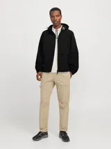 Campera negra de nylon, estilo shell, con capucha y cierre frontal con cremallera. Presenta bolsillos frontales y puños elastizados.