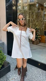 Vestido corto blanco de corte evasé, con escote cuadrado y mangas cortas abullonadas.