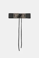 Cinturón ancho de cuero negro con hebilla cuadrada labrada color dorado y cierre con lazos.