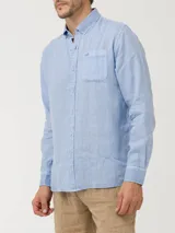 Camisa de lino color verde oliva, con cuello camisero, teñida en prenda. Tiene un bolsillo en el pecho con bordado al tono. De manga larga y calce regular.