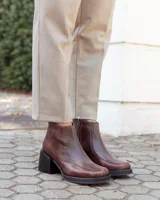 Botinetas de cuero color chocolate, con diseño de textura tipo reptil en el empeine y laterales. Presentan un taco cuadrado de altura media, suela de goma negra y cierre lateral para mayor comodidad.