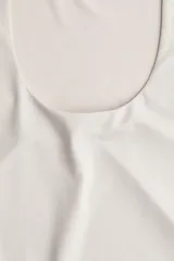 Top sin mangas en microfibra color crudo. Modelo ajustado con leve escote cuadrado y bajo recto. Parcialmente forrado.