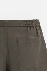 Bermuda regular fit negra confeccionada en tejido de lino. Cintura elástica ajustable con cordón y pliegues frontales. Bolsillos frontales y detalle de bolsillos traseros de plastrón.
