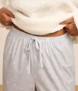 Pijama largo de sherpa color blanco, compuesto por un buzo de cuello redondo y mangas largas con estampa de una carita sonriente y un pantalón con estampa de lunares.
