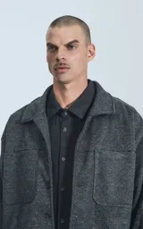 Chaqueta gris de paño con cuello clásico, cierre frontal con botones, bolsillos laterales y corte recto.