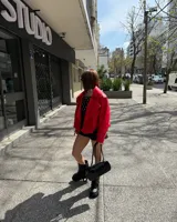 Campera roja de cuero sintético, con cuello solapa, cierre cruzado con botones a presión y cinturón con hebilla.