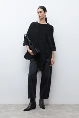 Capa tejida color negro, con cuello redondo, diseño de punto y detalles de lentejuelas. Presenta flecos en el dobladillo.