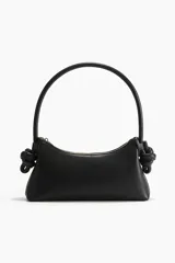 Bolso de hombro pequeño color negro, con cierre superior y asa rígida con nudos decorativos en los extremos. Forro de tafeta.