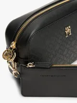 Bandolera negra de Tommy Hilfiger con monograma TH en relieve y logo dorado en el frente. Tiene correa ajustable y extraíble, cierre de cremallera, bolsillo interior con cremallera y monedero extraíble con cremallera.