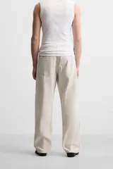 Pantalón de jean color beige, corte recto y relajado, con cintura ajustable con cordón interior, cinco bolsillos, efecto lavado y cierre frontal con cremallera y botón.