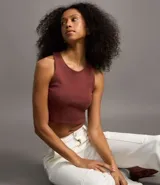 Top cropped sin mangas, color marrón oscuro, de corte ajustado al cuerpo y cuello redondo. Presenta textura acanalada.