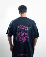 Remera negra de algodón con cuello redondo y mangas cortas. Presenta un estampado pequeño en el pecho con un diseño abstracto en tonos rosa y celeste.