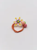 Colero de pelo con elástico naranja y aplique de flor blanca con detalles amarillos, verdes y rosados.