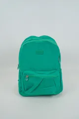 Mochila verde con cierre principal, bolsillo frontal con cierre y dos bolsillos laterales. Tiene un parche con el logo de la marca en la parte superior frontal.