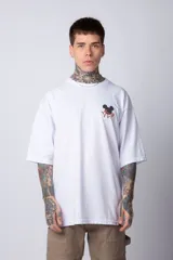 Remera blanca de algodón de corte oversize con mangas cortas y cuello redondo. Presenta un pequeño estampado en el frente con la figura de Mickey Mouse y caracteres orientales.