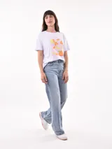 Remera color amarillo claro con estampado de limones, hojas y flores en tonos verdes y grises.