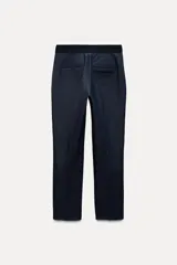 Pantalón tobillero azul oscuro, de tiro medio con cintura elástica en la espalda. Tiene bolsillos delanteros y falsos bolsillos de vivo en la parte trasera. El bajo está acabado con aberturas laterales.
