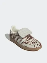 Zapatillas Adidas Samba con estampado animal print de vaca en tonos marrones y blancos, con las tres tiras laterales en blanco y suela de goma color caramelo.