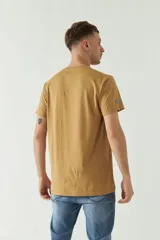 Remera color ocre de manga corta con cuello redondo y estampado frontal con texto en verde y blanco.