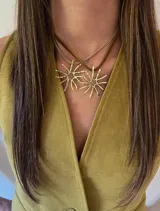 Collar con doble dije dorado en forma de sol con rayos irregulares, engarzado en dos tiras de cuero sintético marrón.