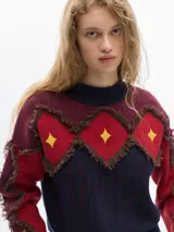 Sweater de lana color borgoña con cuello redondo y apliques de rombos rojos con flecos marrones y estrellas amarillas en el frente y los brazos.