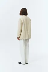 Blazer de lana con mezcla de alpaca en color beige, con cuello sastre, cierre frontal de dos botones y bolsillos laterales con solapa. Presenta una textura suave y vellosa.