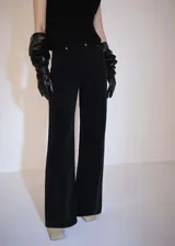 Pantalón de pana negro de corte wide leg, tiro medio, cinco bolsillos y cierre de cremallera y botón.