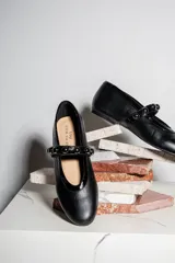Bailarinas negras de cuero con puntera redondeada y tira sobre el empeine con apliques de esferas metálicas.
