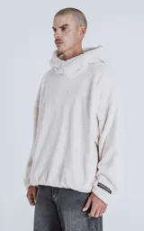 Hoodie blanco de piel de corderito sintético, corte oversize, con capucha ajustable con cordón y bolsillo canguro.