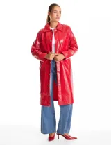 Chaqueta larga tipo trench de charol negro con acabado brillante e impermeable. Presenta cuello con solapa, cierre frontal con botones metálicos plateados y bolsillos laterales. Su diseño es de corte recto y estructura rígida.