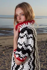 Remera corta tejida a mano en crochet con textura blanca y negra y terminación en pasamanería artesanal con hilado rojo.