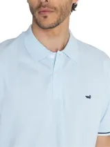 Remera polo celeste de piqué de algodón pima, con cuello clásico, tapeta de dos botones y mangas cortas con ribete azul marino. Logo de la marca bordado en el pecho.