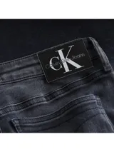Jeans skinny de tiro medio color gris oscuro, con cierre de cremallera y botón, bolsillos delanteros y traseros, y banda lateral con logo de Calvin Klein Jeans.