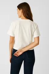 Remera blanca de algodón con estampado de texto y dibujo de naranja.