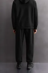 Pantalón jogger color marrón oscuro, corte regular fit, confeccionado en tejido técnico compacto de algodón con elasticidad. Cuenta con cintura elástica ajustable con cordón, bolsillos frontales y bolsillo lateral con cierre de cremallera.