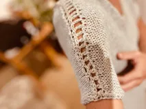 Vestido corto tejido en lurex metálico plateado, con escote en V y mangas cortas.