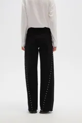 Pantalón jean negro de tiro alto, corte flare y detalle de tachas plateadas en los laterales.