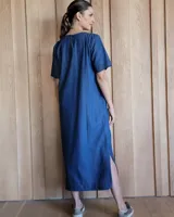 Vestido midi negro con cuello redondo y mangas cortas. Presenta dos bolsillos cuadrados en el pecho y ribetes blancos en cuello, mangas, bolsillos y ruedo.